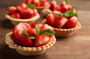 Tartlets ahşap arka plan üzerinde olgun çilek.