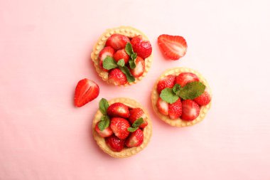 Pembe bir arka plan üzerinde olgun çilek ile üç tartlets. Üstten görünüm.