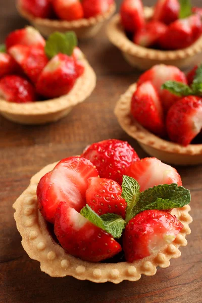 Tartlets ahşap arka plan üzerinde olgun çilek.