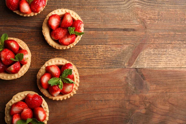 Tartlets ahşap arka plan üzerinde olgun çilek. Üstten görünüm.