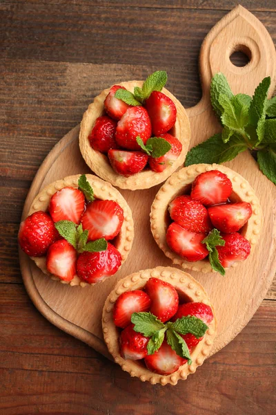 Tartlets ahşap arka plan üzerinde bir kesme tahtası üzerinde olgun çilek. Üstten görünüm.