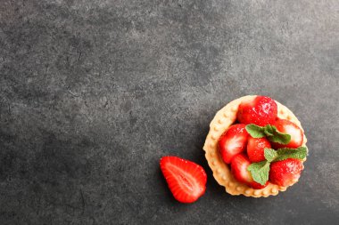 Bir tartı olgun çilek ve siyah bir zemin üzerine nane ile. Üstten görünüm.