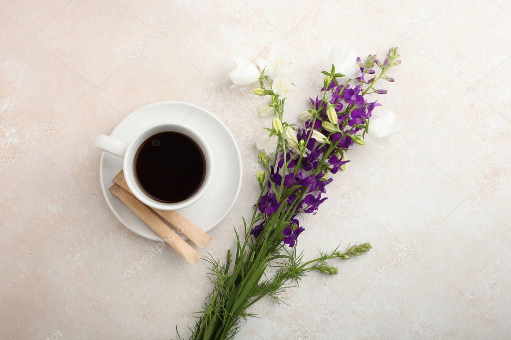 A beautiful bouquet of bells flowers and a cup of tea on a neutral background. Top view, copy space. 