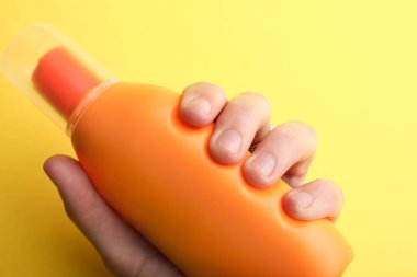 Koruyucu güneş krem sarı bir arka plan üzerinde elinde.