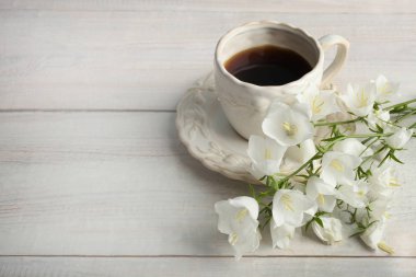 Çan çiçek ve bir fincan çay ahşap arka plan üzerinde güzel buket.