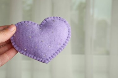 El işlemeli kalp cama bir kadının elinde.