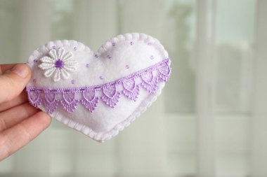 El işlemeli kalp cama bir kadının elinde.