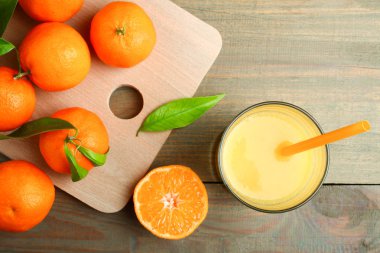 Mandalina bir kesme tahtası ve ahşap arka plan üzerinde taze sıkılmış meyve suyu. Üstten görünüm.