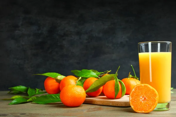 Mandarins and freshly squeezed juice on a wooden table on a black background.