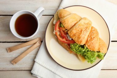 Kruvasan sebze ve bir fincan çay bir ahşap zemin üzerine.