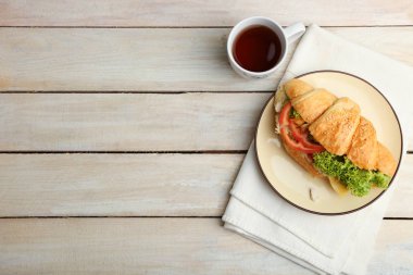 Kruvasan sebze ve bir fincan çay bir ahşap zemin üzerine.