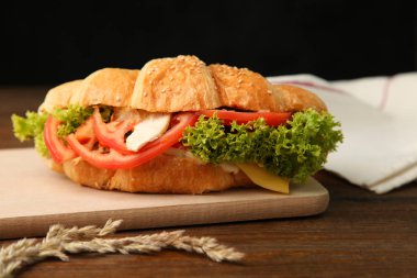 Kruvasan sebze kesme tahtası üzerinde siyah bir zemin üzerine ahşap bir masa ile.