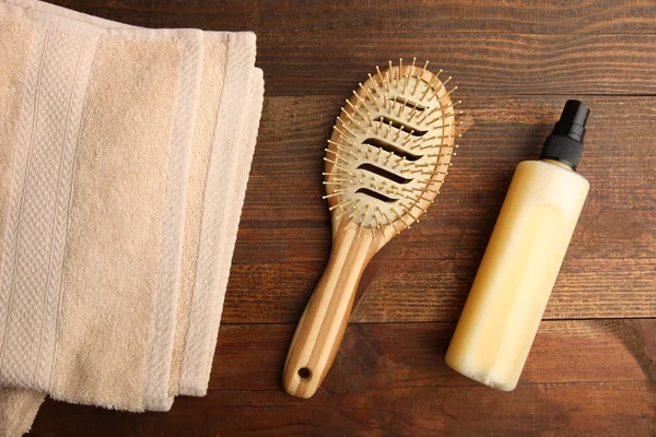 Spray for hair, comb and towel on wooden background. Top view