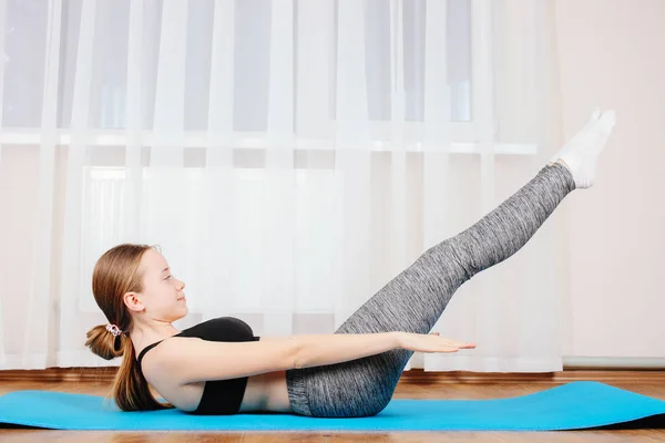 Young girl is sporting gymnastic mate. Concept home training.