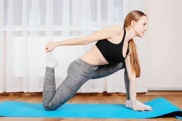 Young girl is sporting gymnastic mate. Concept home training.