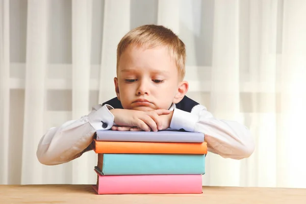 Tired schoolboy sleeps on pile of books. Concept school.