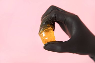 Pembe bir arka plan üzerinde elinde şeker yapıştırın. Kavram epilasyon.