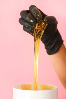 Pembe arka plandaki kılları çıkarmak için şeker macunu. Epilasyon kavramı. 