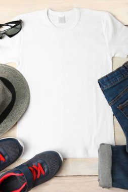 Aksesuarlar, tişört ve spor ayakkabı ahşap arka plan üzerinde. Üstten görünüm. Aksesuarlar, kot pantolon, tişört