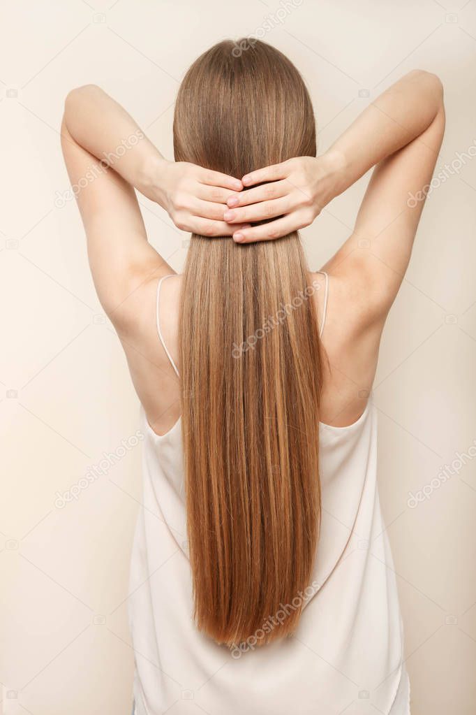 Girl with long blond hair on beige background. Concept hair care.