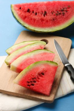 Dilim karpuz kesme tahtası üzerinde mavi arka plan üzerinde.