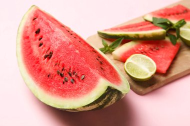 Karpuz kesme tahtası üzerinde pembe bir arka plan üzerinde limonlu.
