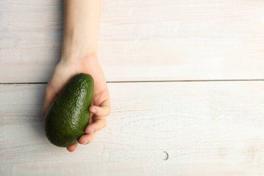Olgun avokado ahşap arka plan üzerinde elinde. Üstten görünüm. Kopya alanı.
