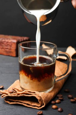 Cam siyah arka plan üzerine süt dökülür. Kahve yapma kavramı.