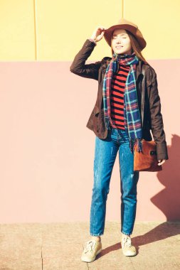 Pembe ve sarı duvara sonbahar giysileri kızı.