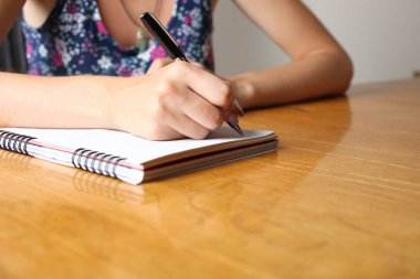 Kadın defter masada yazıyor. Kavram yazar.