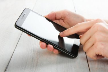 Modern smartphone ahşap arka plan üzerinde elinde. Giydirin-up.