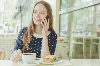 Kız ile kahve masada oturur ve lazanya yiyor. Açık.