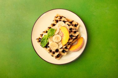 Şeftali ve yeşil renkli bir tabağa muz ile Belçika waffle. Kavram tatlı. Üstten görünüm.