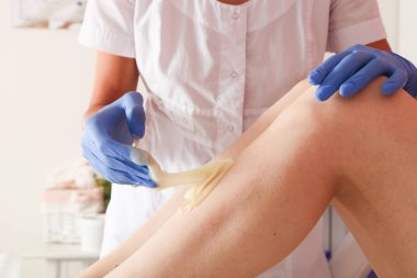 Master beyaz tıbbi elbise güzellik salonunda yapıştırın Depilasyon bacaklar kızla şeker yapar.