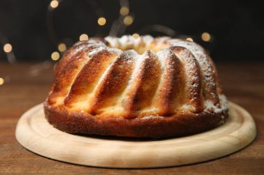 Pişmiş peynir pasta kesme tahtası üzerinde sarı ışık siyah zemin üzerine ahşap masa üzerinde.