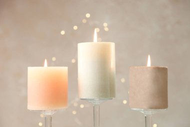 Cam şamdanlar sarı ışık ile nötr arka plan üzerinde üç yanan mumlar.