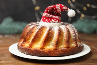 Noel kek siyah arka plan üzerine ahşap masa üzerinde plaka üzerinde kırmızı Noel şapkalı.