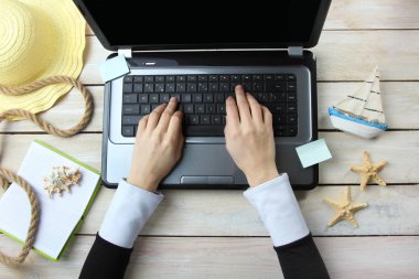 Yaz tatili, turizm ve tatil. Kadın ahşap arka plan üzerinde online rezervasyon için dizüstü bilgisayar kullanır. Yaz dekor. Üstten görünüm.