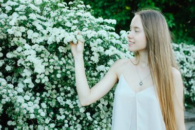 Güzel gülümseyen beyaz kadın yeşil çiçekli çalı, bahar açık gün ışığı durumda. Kopya alanı.