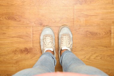 Kadın mavi kot pantolon ve ahşap arka plan üzerinde şık evrensel rahat spor ayakkabılar bacaklar. Kopya alanı.