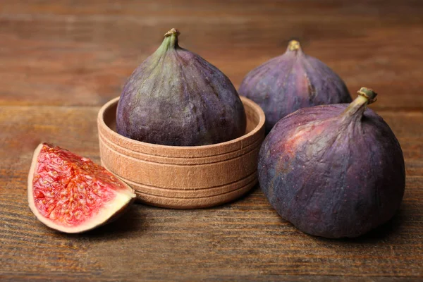 Ahşap arka plan üzerinde olgunlaşmış incir bütün ve kesilmiş. Sağlıklı gıda.