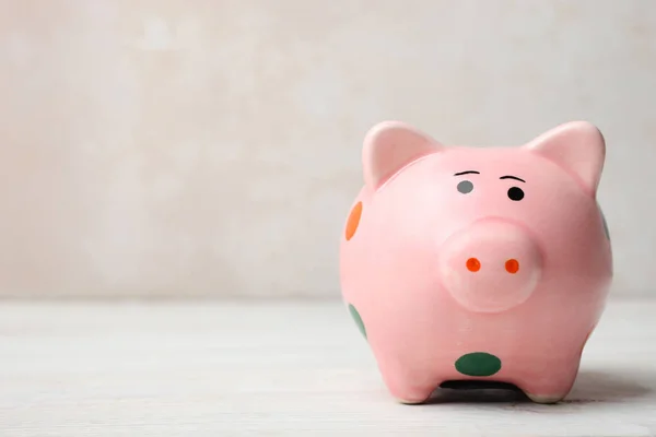 One pink pig piggy bank in polka dot standing on wooden table on neutral background. Concept saving. Copy space.