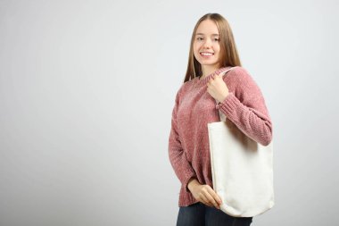 Güzel beyaz gülümseyen kız tarafsız arka plan üzerinde beyaz Eko çantalı.