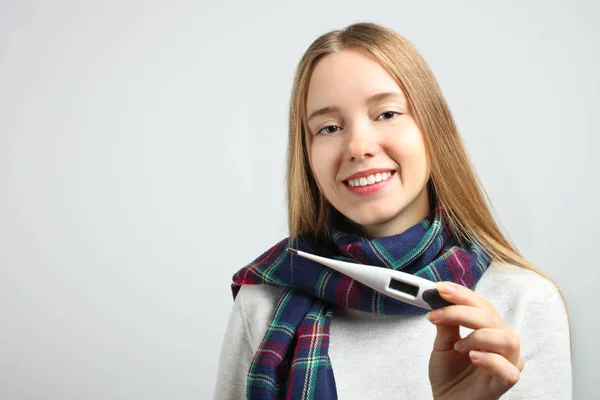 Gadis Tersenyum Dengan Syal Dengan Termometer Elektronik Dengan Latar Belakang — Stok Foto