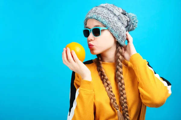 美丽的滑稽的高加索女孩在冬天帽子与明亮的橙色在蓝色背景 — 图库照片