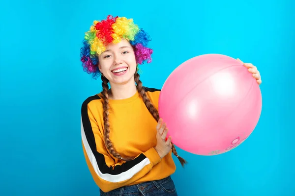 微笑的愉快的女孩小丑与大气球在蓝色背景 — 图库照片