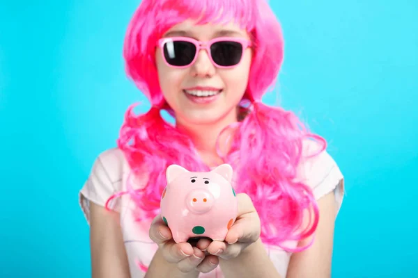 美しい笑顔の少女の明るいピンクの髪と青色の背景色に彼女の手で貯金 コンセプト貯蓄 — ストック写真