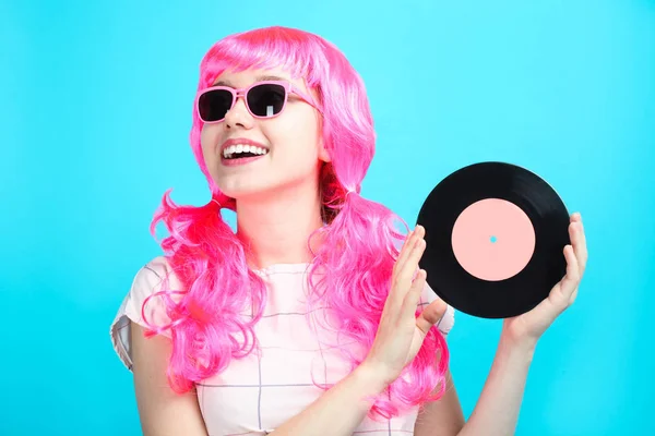 美丽的微笑的幸运的女孩与明亮的粉红色头发在礼服与老复古乙烯基记录在蓝色背景 概念音乐 — 图库照片