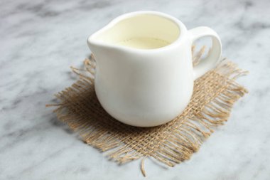 Mermer zemin üzerine çuval bezi üzerinde beyaz süt kabı.