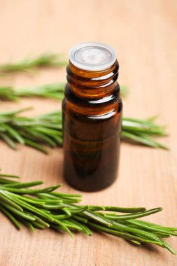 Taze yeşil biberiye dalı ve aroma petrol şişe ahşap arka plan üzerinde. Kavram Aromaterapi, tıp.